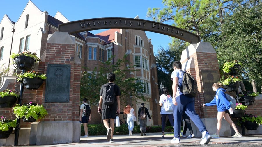 University of Florida campus entrance with students walking beneath the archway.