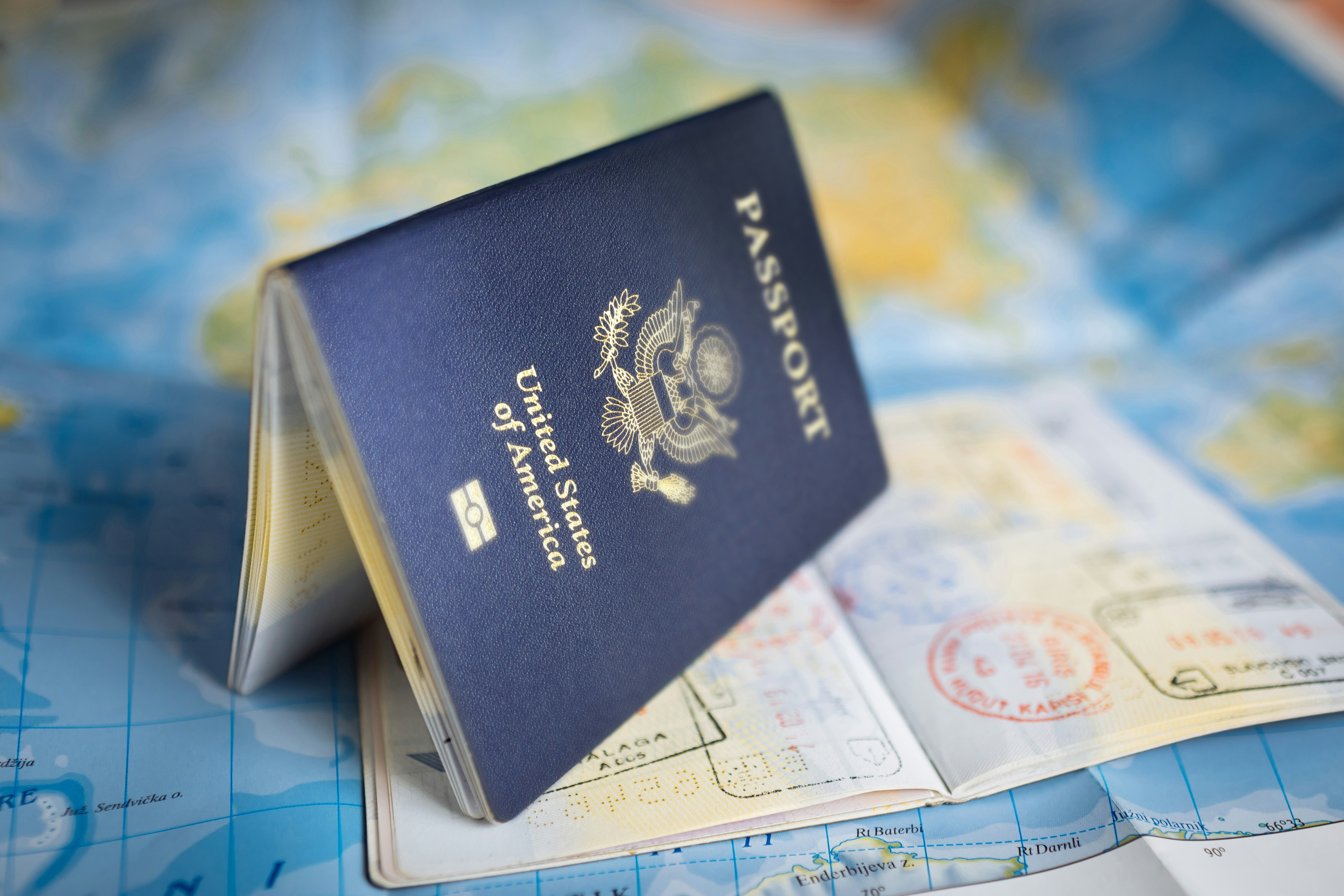 United States passport open on a world map with visa stamps